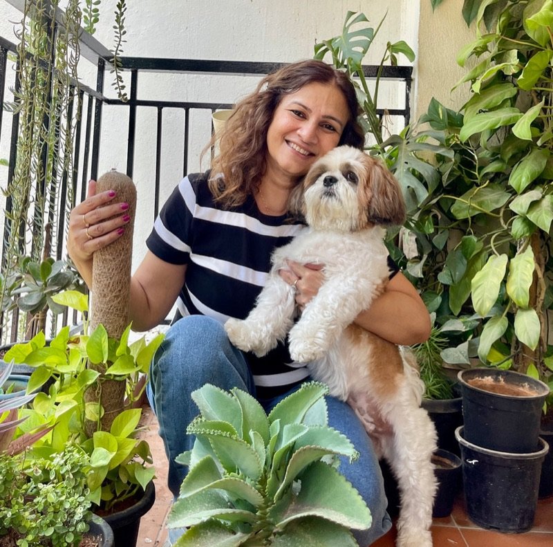 Anupma Gupta at home among her plants, holding her dog